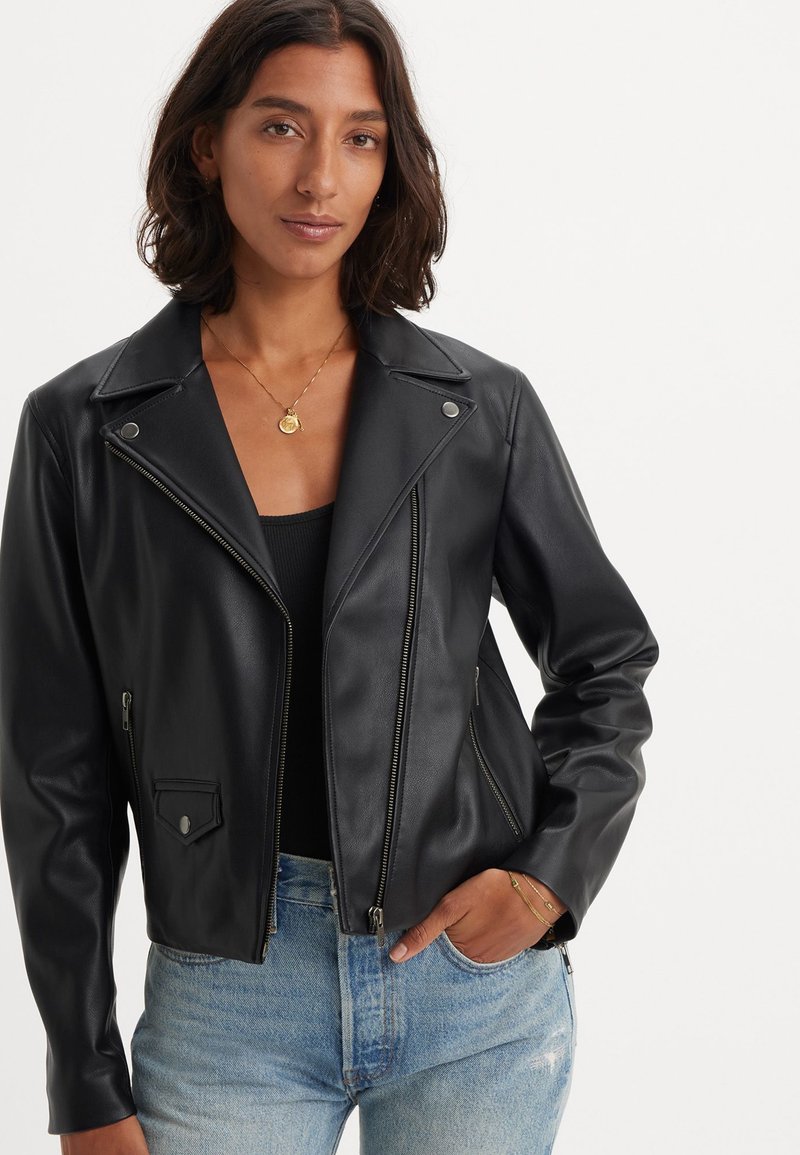 Musta nahkainen moottoripyörätakki, jossa on lovettu kaulus, edessä vetoketju ja kaksi sivu vetoketjullista taskua. Sujuva pinta; tiukka muotoilu.