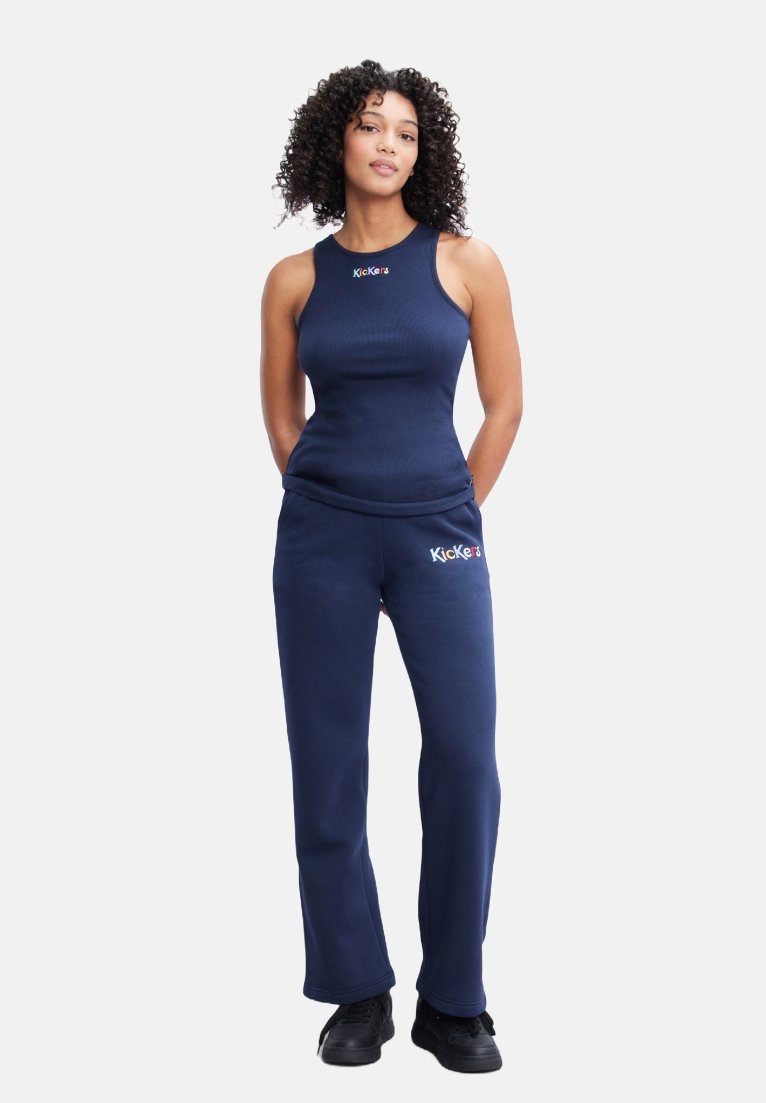 Canottiera a coste blu con logo, abbinata a pantaloni jogger blu, caratterizzata da una vestibilità rilassata. Il materiale appare morbido e confortevole, adatto per un abbigliamento casual.