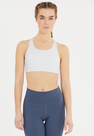 Ljust grå sportbh i mjukt material med racerback-design. Tillsammans med höga marinblå tights med subtila sömdetaljer.