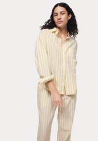 Katoenen pyjamapakket met gele stof met blauwe verticale strepen, een shirt met een relaxte pasvorm en knoopsluiting, en bijpassende gestreepte broek.