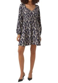 Robe à motifs marine et crème avec un col en V, de longues manches bouffantes et une taille froncée. Fabriquée en tissu léger, longueur au-dessus du genou.