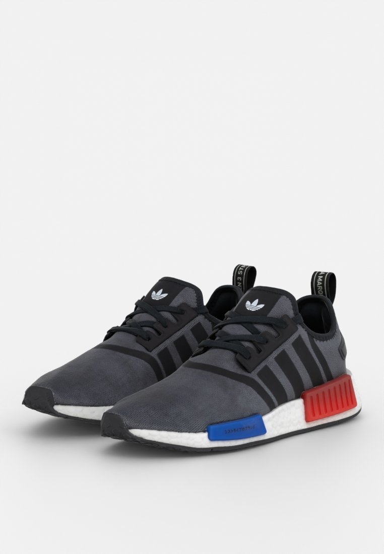 Schwarze und graue Sportschuhe mit einem strukturierten Obermaterial, drei schwarzen Streifen, einer weißen Zwischensohle und bunten roten und blauen Akzenten an der Sohle.