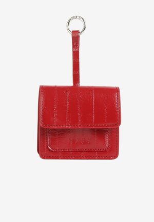 Rdeč ovitek za ključe iz umetnega usnja z teksturirano površino, zapiranjem na jeziček in vbočenim logotipom na sprednji strani. Ima kovinski obroč za pritrditev.