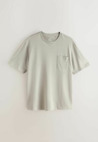 T-shirt gris clair à manches courtes et col rond, avec une petite poche poitrine, présenté à plat sur un fond uni.