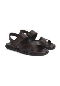 Bruine leren sandalen met kruisbanden, open hak en platte zool. Glad oppervlak, minimalistisch ontwerp en duurzame stikdetails.