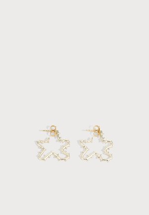 Paire de boucles d'oreilles clous en métal doré en formes abstraites et irrégulières d'éclats d'étoiles sur fond blanc.