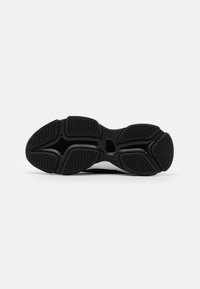 Semelle de sneaker en caoutchouc noir avec des motifs de bande de roulement texturés et un centre lisse. Présente un design hexagonal dans la semelle intermédiaire pour une meilleure adhérence.