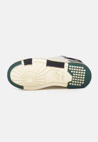 Suola della scarpa con una suola in gomma verde strutturata, intersuola color crema e un motivo di battistrada dettagliato. Accenti neri e grigi nella parte superiore.