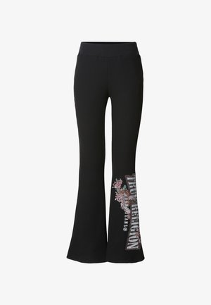 Pantalon noir côtelé évasé avec une large ceinture. Présente un motif floral brodé et un texte imprimé sur la partie inférieure de la jambe gauche.