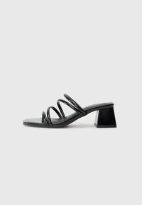 Black heeled sandal with a square toe, featuring three twisted straps on the upper and a chunky square heel. Smooth, glossy material.