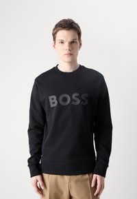 Zwarte sweatshirt gemaakt van een katoenmix; heeft een groot, glanzend 'BOSS' logo in het midden; ronde halslijn; lange mouwen; geribbelde manchetten.