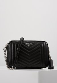 Schwarze gesteppte Leder-Umhängetasche mit Chevron-Muster, silbernem Logo, Ketten- und Ledertragegurt sowie Quaste.