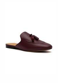 Scarpa slip-on in pelle bordeaux con punta affilata, dotata di eleganti nappine decorative e suola piatta. Texture liscia con cuciture minime.