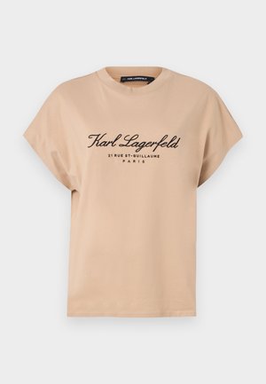 Beige bomull T-skjorte med rund hals, korte ermer og trykt svart tekst foran, som viser merket og steddetails.