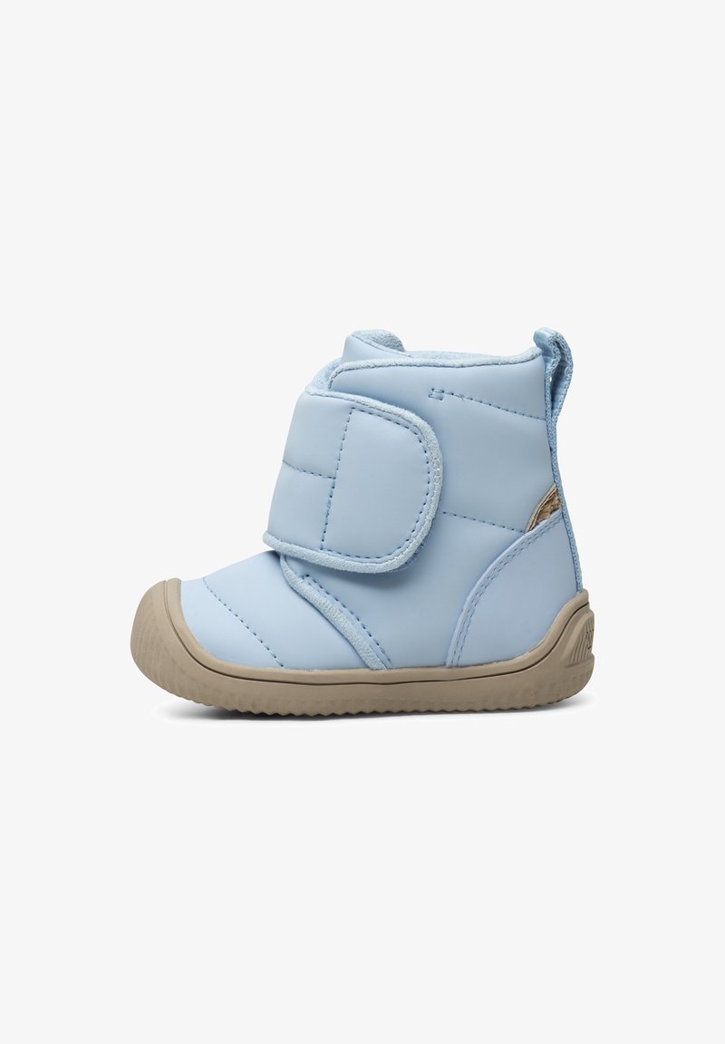 Bota acolchada de color azul claro con una correa de Velcro, parte superior sintética suave y suela de goma beige, con una lengüeta en el talón para facilitar su colocación.