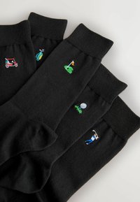 Calze nere in cotone con colorati ricami a tema golf, tra cui un carrello da golf, mazze, palla e golfista in varie posizioni.