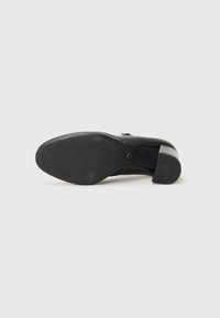 Schwarze Damenschuhsohle aus strukturiertem Gummi. Verfügt über einen Blockabsatz und eine glatte obere Sektion. Markierungsdetail auf dem Absatz eingeprägt.