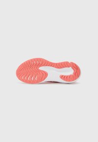 Semelle de chaussure de sport avec un design ondulé et texturé en caoutchouc corail et blanc ; les rainures offrent adhérence et flexibilité.