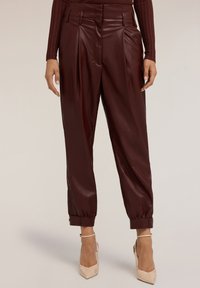Bordeaux faux leren broek met plooien, taps toelopende boorden en zijritsen. Gladde textuur met een glanzende afwerking. Ontworpen met riemlussen.