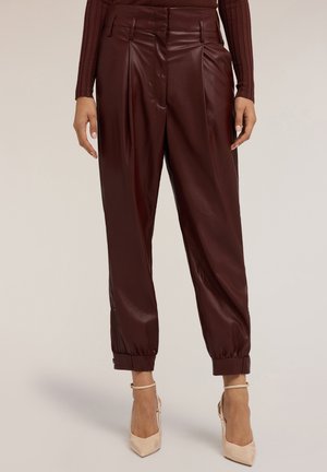Burgunderfarbene Kunstlederhose mit Falten, schmalen Bündchen und seitlichen Reißverschlüssen. Glatte Textur mit glänzendem Finish. Mit Gürtelschlaufen versehen.