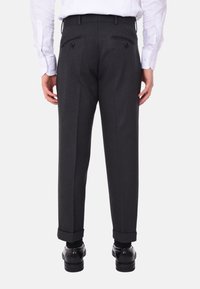 Pantaloni personalizzati grigio scuro a taglio slim, con due tasche posteriori, trama sottile e risvolti all'orlo. Scarpe nere visibili.