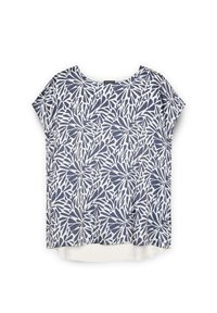 Valkoinen lyhythihainen toppi, jossa on tummansiniset lehdet, pyöreä pääntie, rento malli ja hieman pidempi takahame, jonka rakenne on sileä.