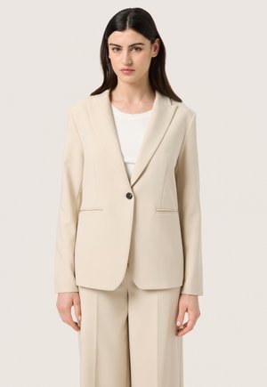Beige skræddersyet blazer lavet af glat stof. Har en enkelt knaplukning og sidelommer. Strukturerede skuldre og et klassisk reversdesign.
