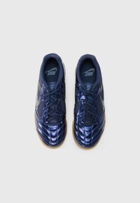 Ναυτικό μπλε αθλητικά παπούτσια Nike με γυαλιστερή επιφάνεια, πλέγμα στα πλαϊνά πάνελ και μαύρες κορδόνες. Η σόλα από καουτσούκ γκασμά παρέχει αντίθεση.