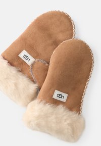 Manoplas de ante marrón con un puño de piel de color beige, con costuras blancas y una pequeña etiqueta de marca en una de las manoplas. Textura suave y forma redondeada.