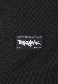 Panneau en tissu noir avec le texte blanc "NEW YORK CITY SKATEBOARDS" et le logo de style graffiti "ZOO YORK" avec "NYC" et "EST. 1993" en dessous.