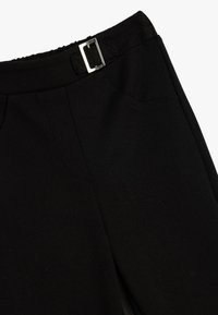 Zwarte broek met een gladde textuur, voorzien van een zilveren rechthoekige riemgesp en zakken aan de zijkant. Getailleerde pasvorm met een gestikt ontwerp.