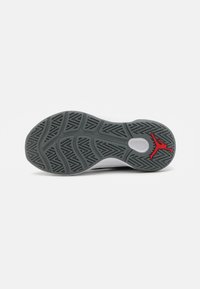 Grå gummisko såle med et teksturert mønster og en rød Jumpman-logo. Har tydelige traction riller og et sirkulært midtområde.