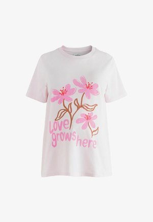 Hvid bomulds-T-shirt med et blomsterprint med pink blomster og brune stilke. Teksten "love grows here" i pink, stiliseret skrifttype. Korte ærmer.