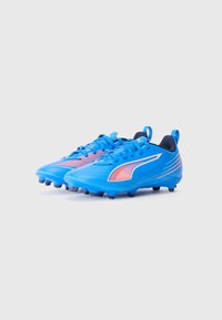 Las botas de fútbol azules cuentan con una parte superior sintética texturizada, acentuada por una franja naranja contrastante y tacos negros en la suela.