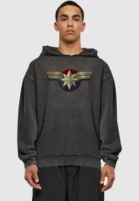 Hoodie nero con una grande grafica di una stella e ali in rosso, oro e blu sulla parte anteriore. Il tessuto sembra morbido e ha una vestibilità comoda.