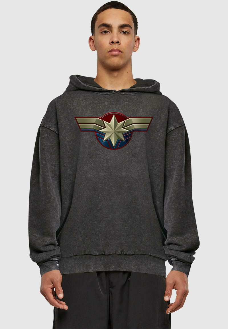 Sudadera negra con un gran gráfico de una estrella y alas en rojo, oro y azul en la parte frontal. La tela parece suave y tiene un ajuste relajado.