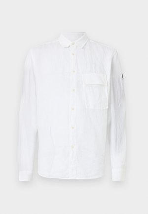 Vit linne skjorta med långa ärmar, knäppt fram, spetskrage, en bröstficka och logotyp på ärmen. Mjuk textur.