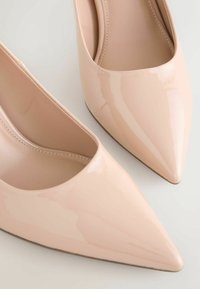 Beežid läikiva pealisnahaga terava ninaosaga kontsakingad, millel on madal lõige ja minimaalne õmblus servade ümber.