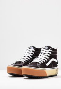 Černé plátěné vysoké tenisky s bílými akcenty, s béžovou a oranžovou platformou a kostkovaným detailem na patě.