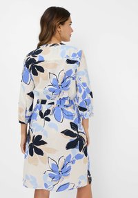 Abito A-line floreale con motivi blu, neri e beige. Presenta maniche a tre quarti e una cintura in vita, realizzato in tessuto leggero.