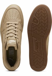 Sneaker beige Puma con punta forata, lacci, colletto imbottito, logo Puma sulla linguetta e suola in gomma dettagliata con marchio Puma.