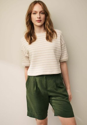 Kortærmet, tekstureret bluse med beige og hvide striber, parret med grønne linnedshorts, der har sidelommer og en afslappet pasform.
