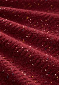 Tissu texturé bordeaux avec des éclats multicolores éparpillés, présentant un motif côtelé et une surface douce.