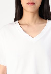 Hvit bomulls V-hals t-skjorte med korte ermer. Glatt tekstur og minimalistisk design, med en subtil krage og avslappet passform.
