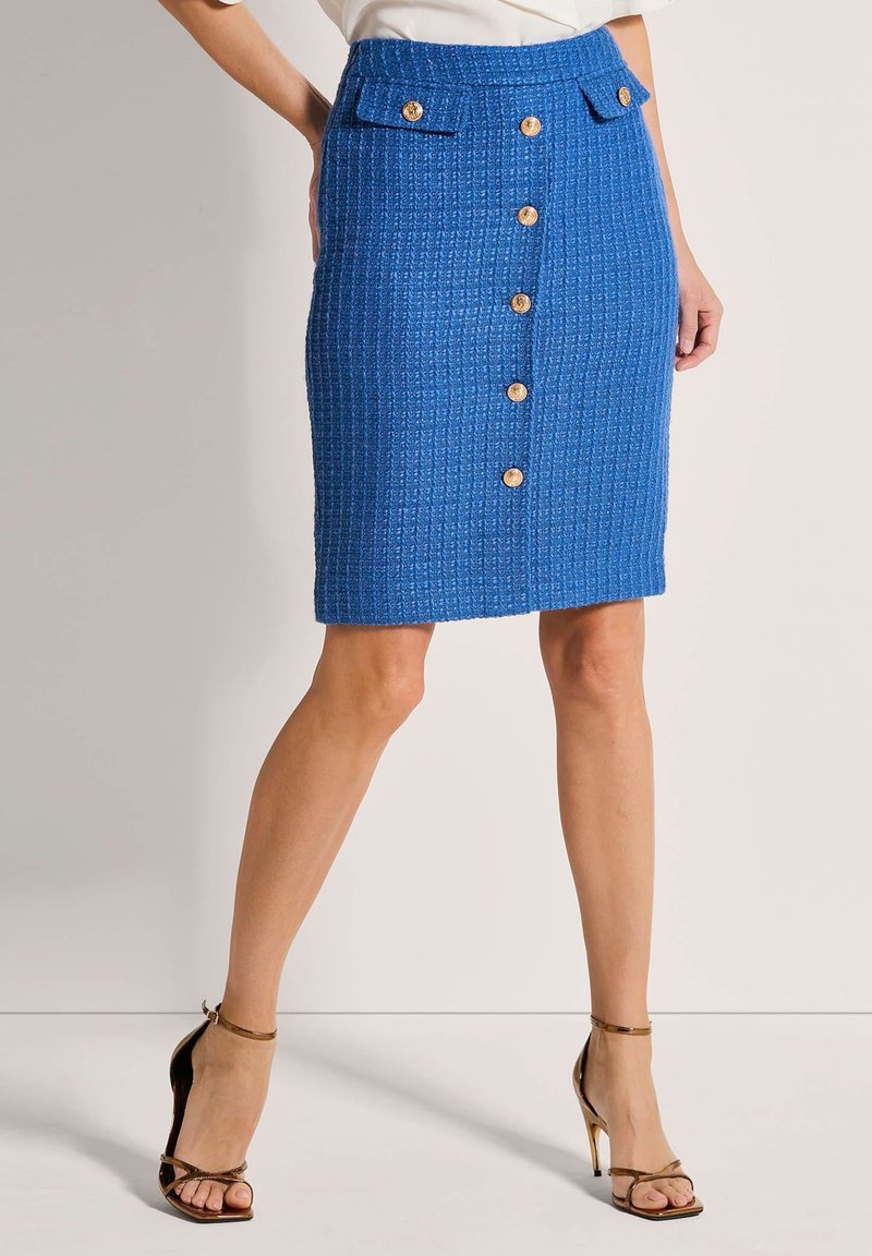Blauer, strukturierter Bleistiftrock mit taillierter Passform, ausgestattet mit vorderen Knöpfen und Seitentaschen. Akzentuiert mit goldfarbenen Knöpfen.