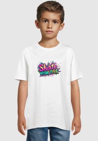 Hvit bomull t-skjorte med en fargerik grafisk trykk med "Skate New York" i rosa, blått og grønt på forsiden. Korte ermer, rund hals.