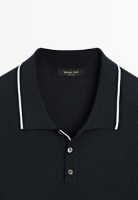 Polo shirt blu navy con texture a coste, dettagli bianchi sul colletto e patta con tre bottoni. L'etichetta leggibile recita "Massimo Dutti."