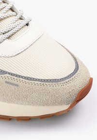 Zapatillas con parte superior de malla en crema y beige, con acentos grises, superposiciones de gamuza, cordones texturizados y una suela de goma marrón.
