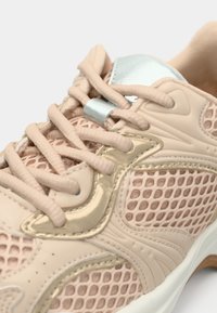 Αθλητικό παπούτσι σε ανοιχτό ροζ με διχτυωτό πάνω μέρος, λαμπερά χρυσά στοιχεία, μπεζ κορδόνια και μεταλλική ασημί λεπτομέρεια στη γλώσσα. Λευκή λάστιχη σόλα.