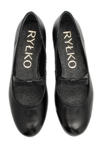 Un par de zapatos planos de cuero negro con pequeños lazos en la parte superior y plantillas doradas "RYŁKO", vistos desde arriba sobre un fondo blanco.